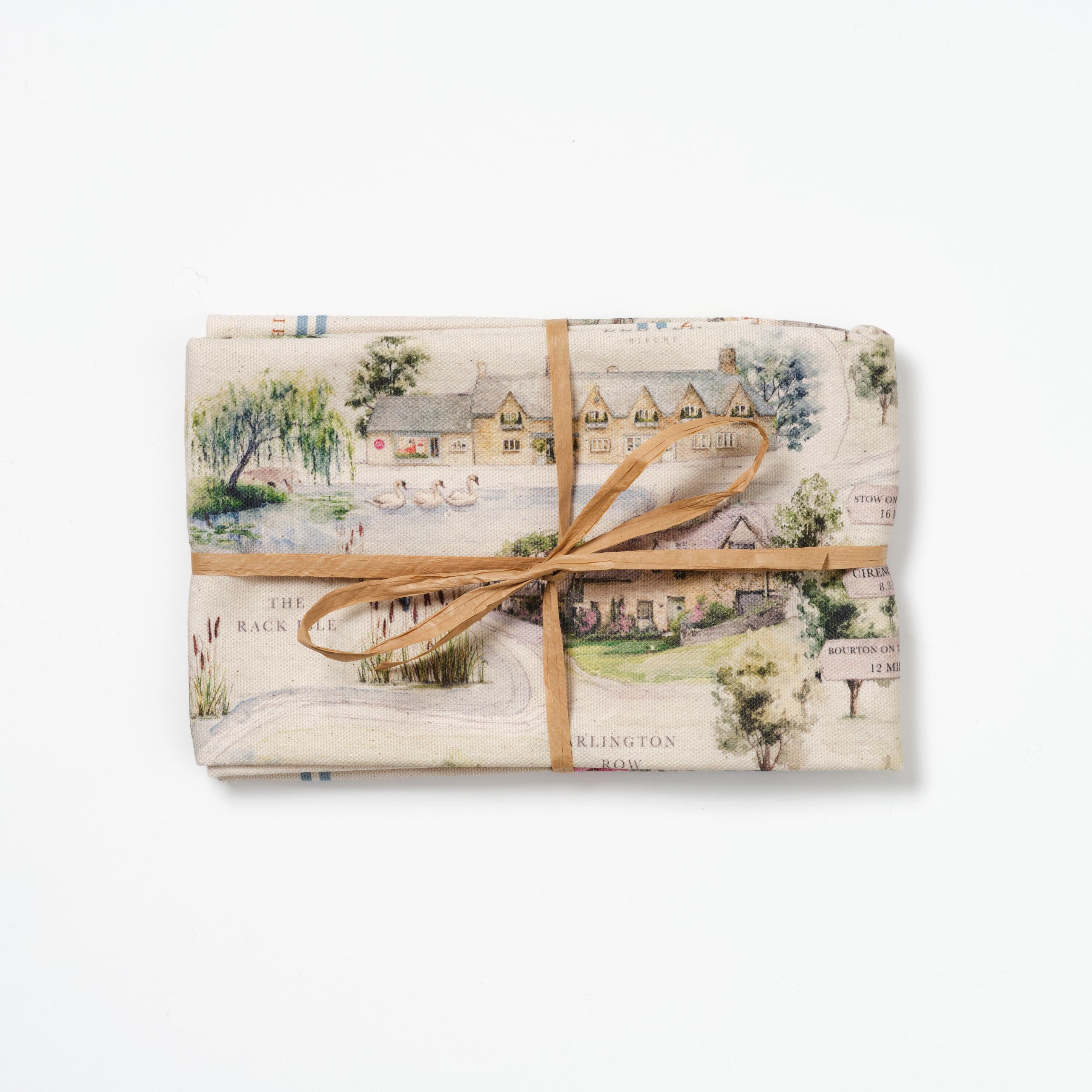 Folded Bibury Map tea towel tied with raffia on a white background.