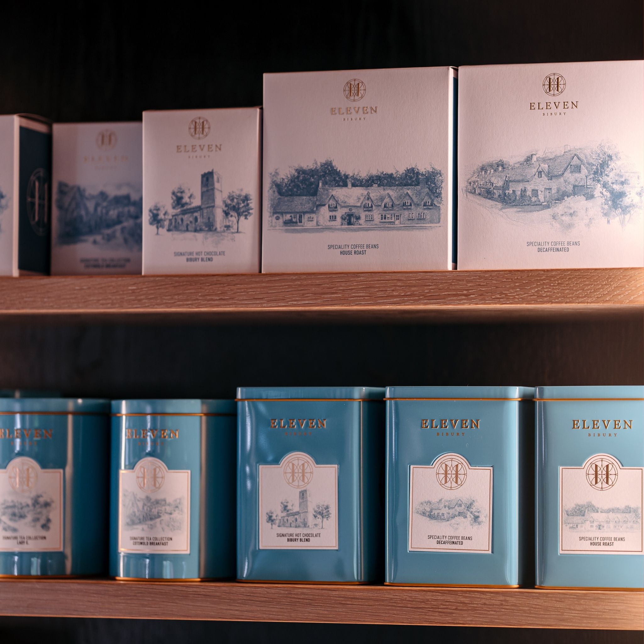 Tea, coffee and hot chocolate packages with 'Eleven Bibury' branding on a wooden shelf