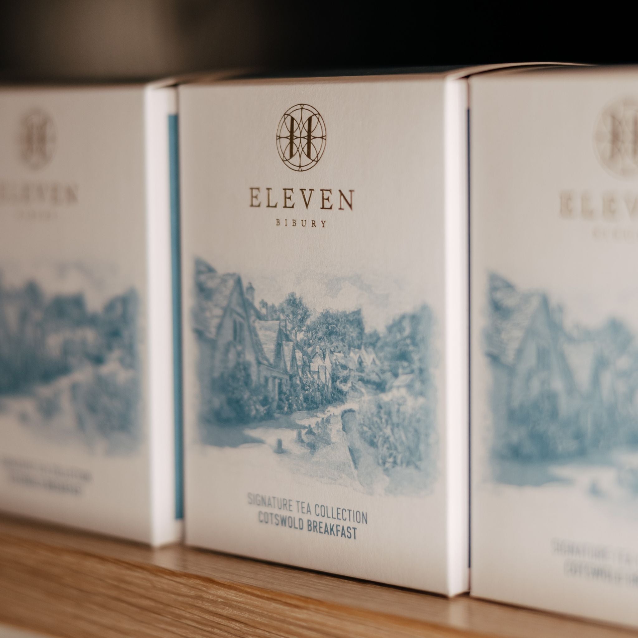 Three boxes of Eleven Bibury tea on a wooden surface