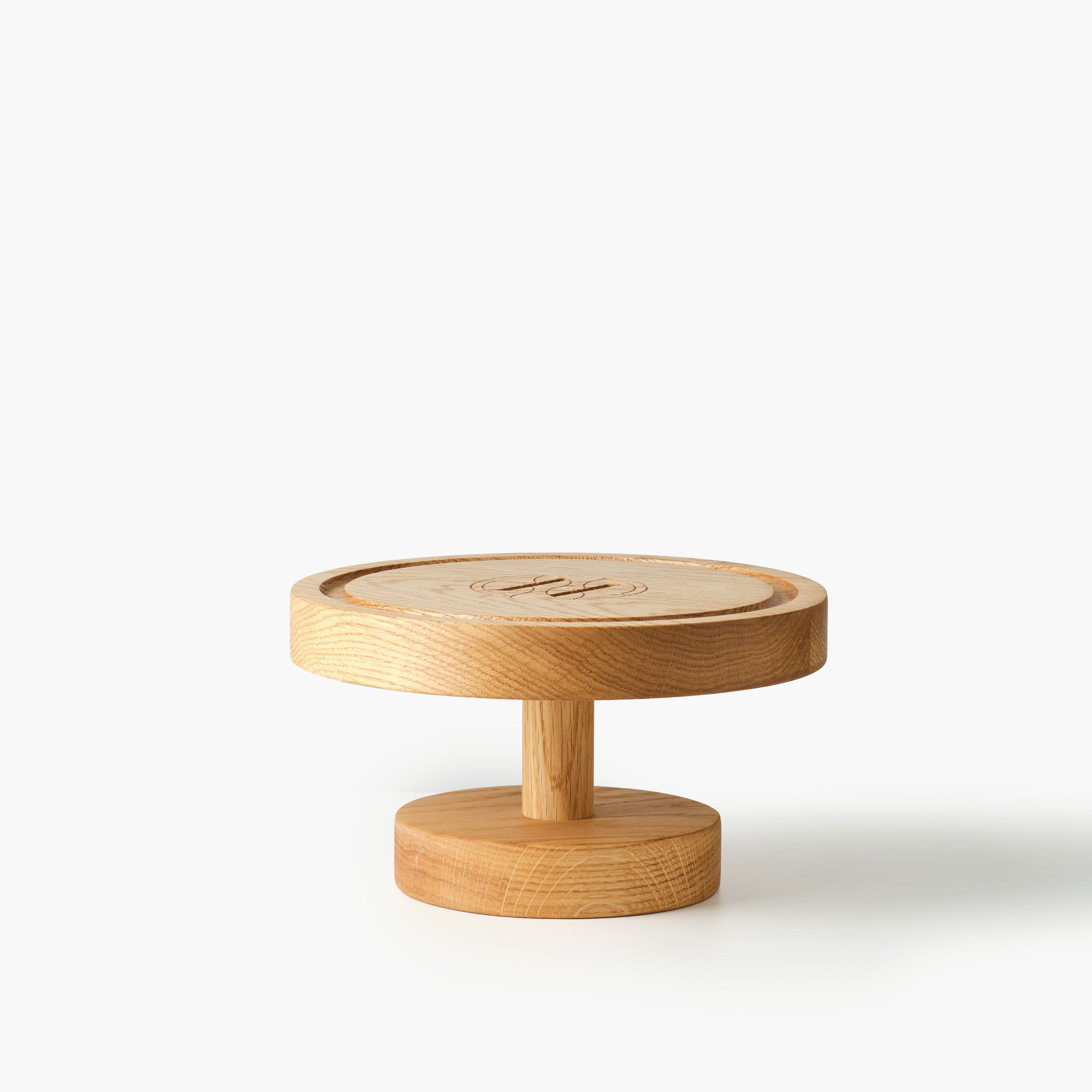 Round wooden cake stand engraved with Eleven Bibury logo on a white background