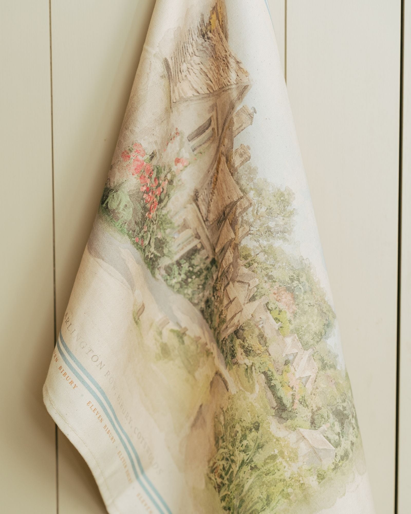 Decorative towel with nature-themed design hanging on a painted surface