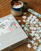 Jigsaw puzzle with pieces scattered on a wooden surface next to a cup of coffee.
