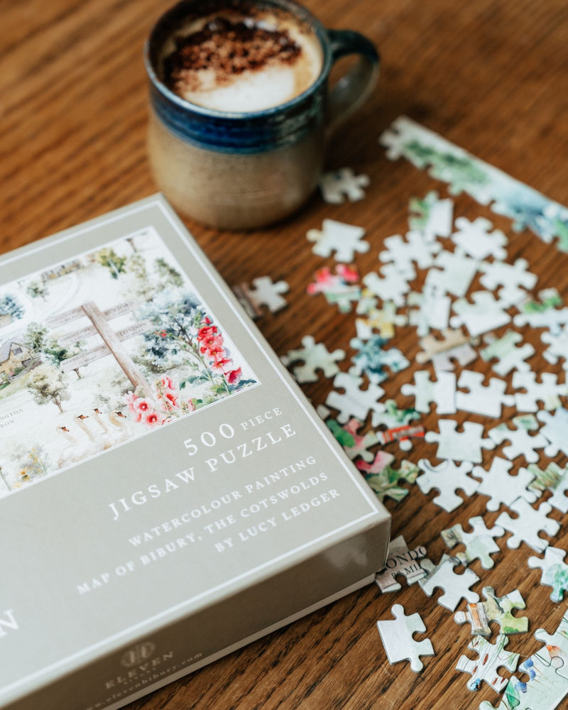 Jigsaw puzzle with pieces scattered on a wooden surface next to a cup of coffee.