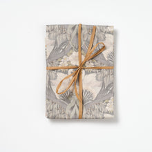 Bibury Swan apron folded and tied with raffia on a white background.