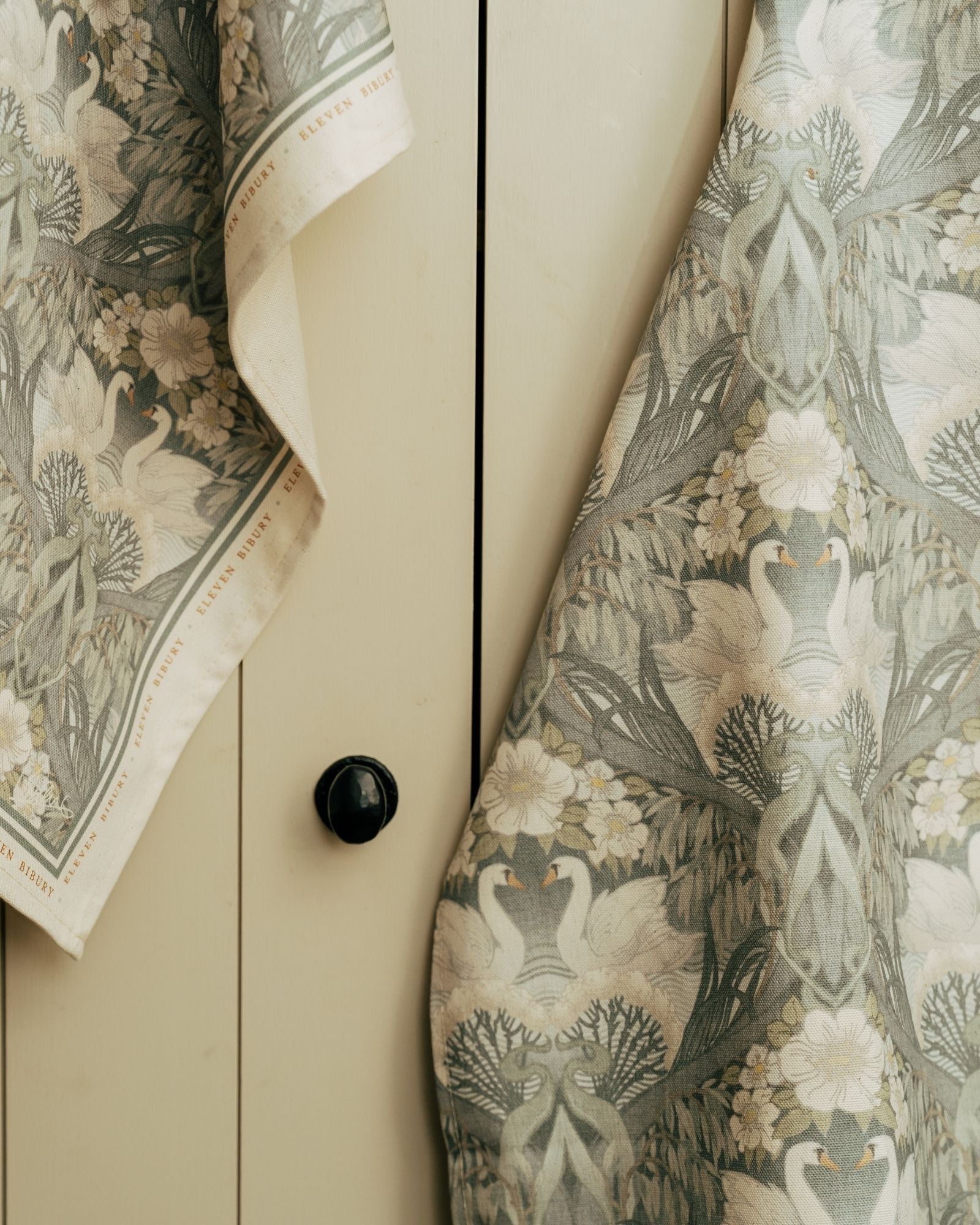Close-up of a tea towel and apron with Bibury Swan fabric