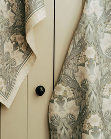 Close-up of a tea towel and apron with Bibury Swan fabric