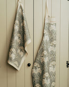 Floral-patterned apron and towel hanging on a wooden door.