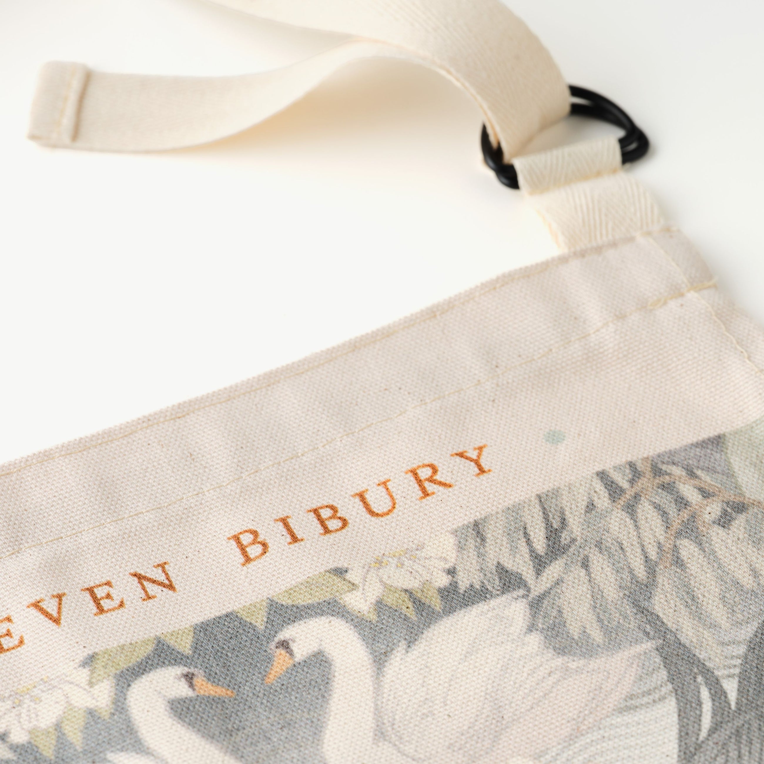 Close up of Bibury Swan designed apron 'Eleven Bibury' text on a white background
