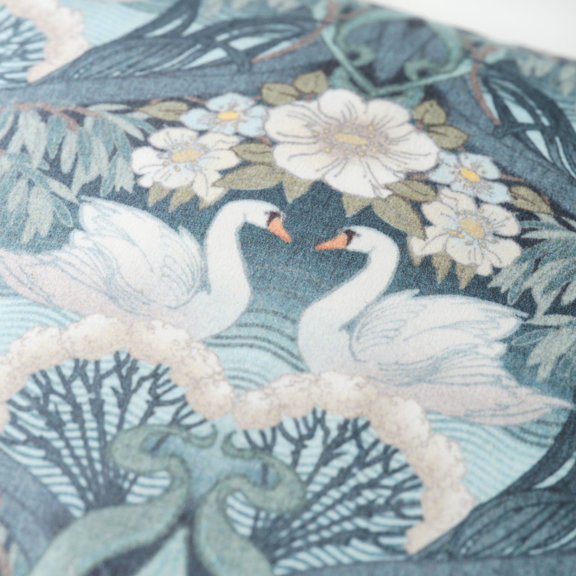 Close up of decorative Bibury Swan fabric with swans and floral patterns on a blue background