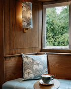 Cozy corner with a cushioned bench, cup of coffee, and window view