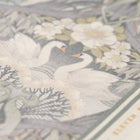 Close up of Bibury Swan tea towel with swan and floral pattern on a grey background
