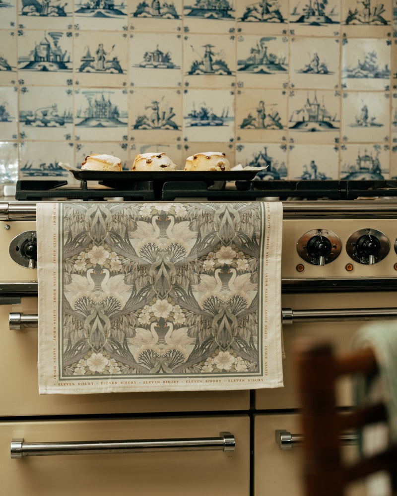 Stove with a decorative towel hanging on the handle against a patterned wall.