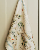 Decorative towel with vintage-style map and illustration design against a painted wooden background