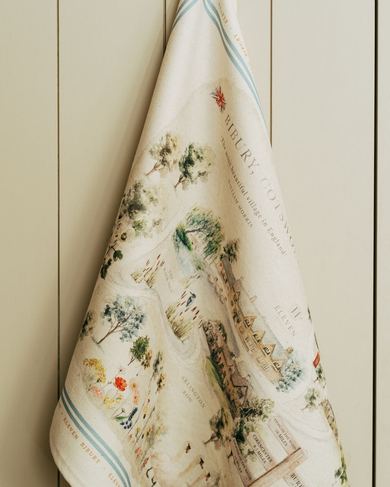 Decorative towel with vintage-style map and illustration design against a painted wooden background