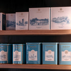 Tea, coffee and hot chocolate packages with 'Eleven Bibury' branding on a wooden shelf