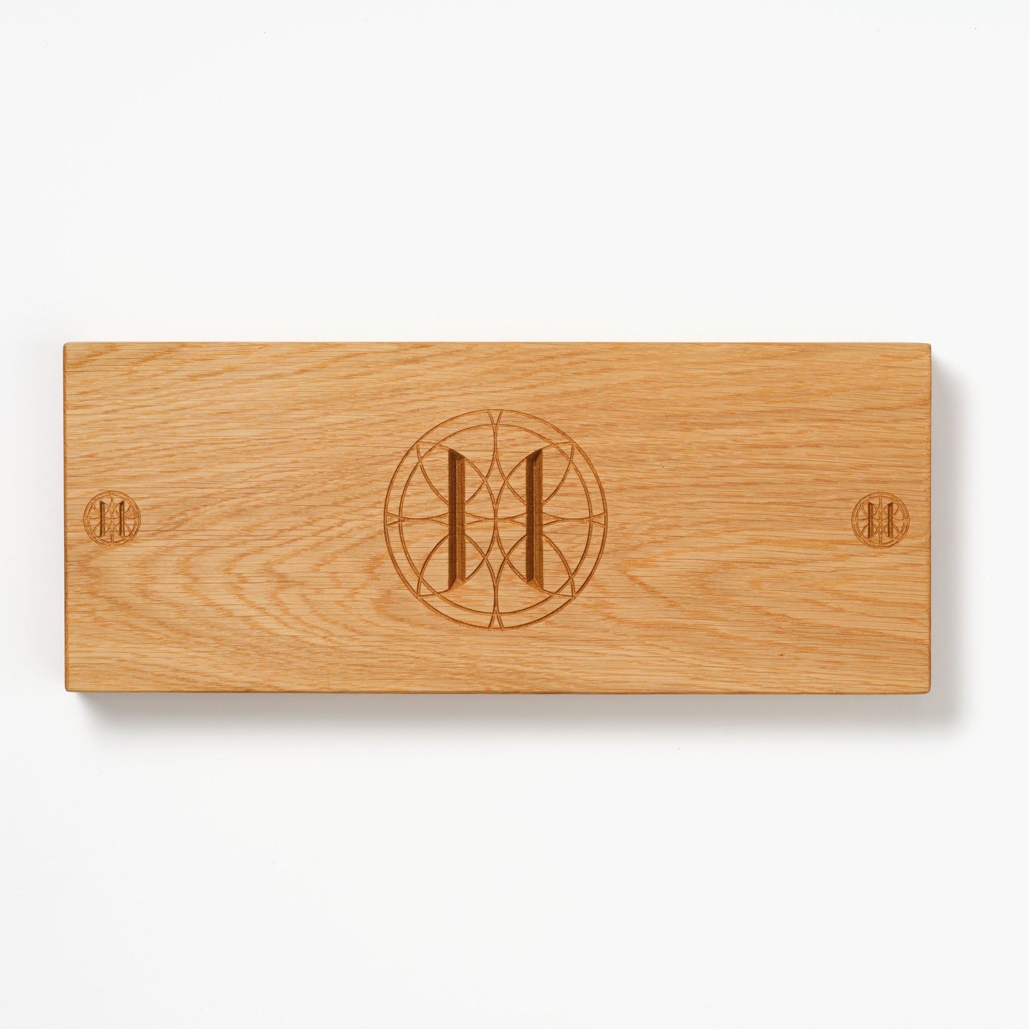 Oak charcuterie board with engraved Eleven Bibury logo on a white background