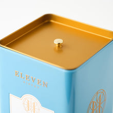 Blue metal tin with gold lid and 'ELEVEN Bibury' branding on a white background