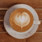 Cappuccino with heart-shaped latte art on a wooden surface