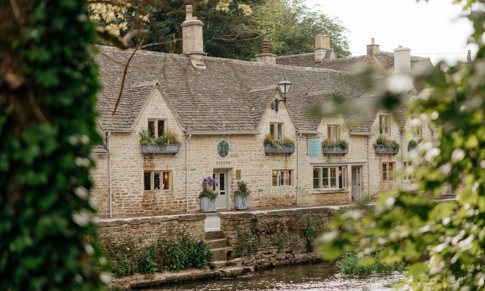 Front of Eleven Bibury along river with greenery in the foreground