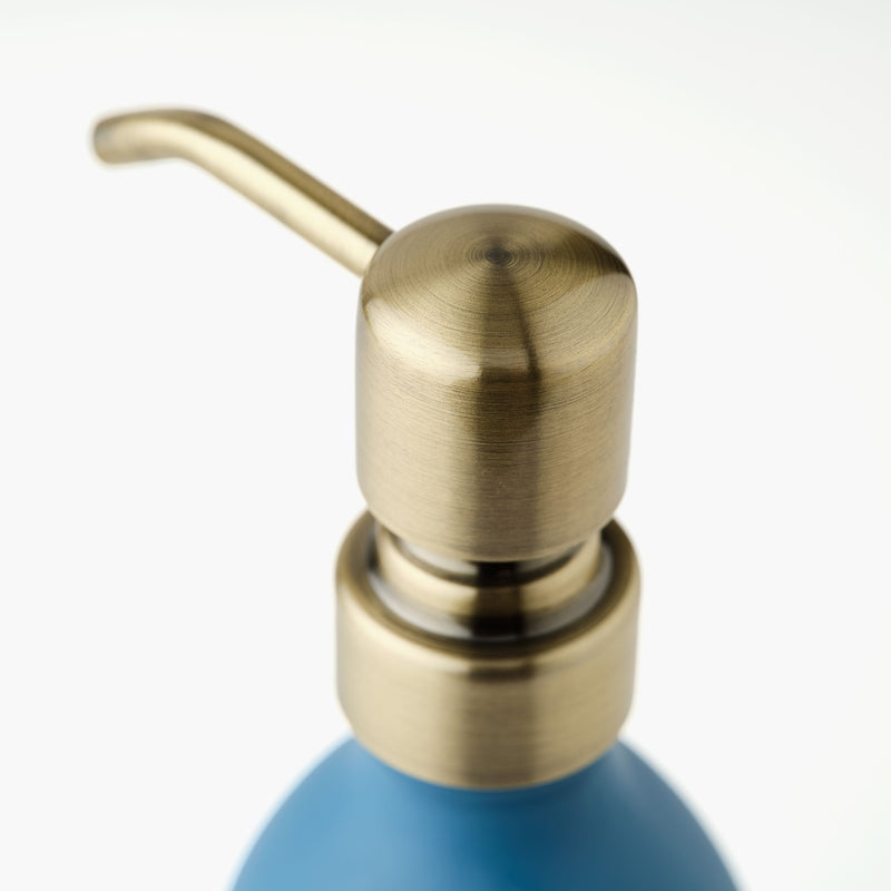 Close up of a brass pump on a blue bottle with a white background