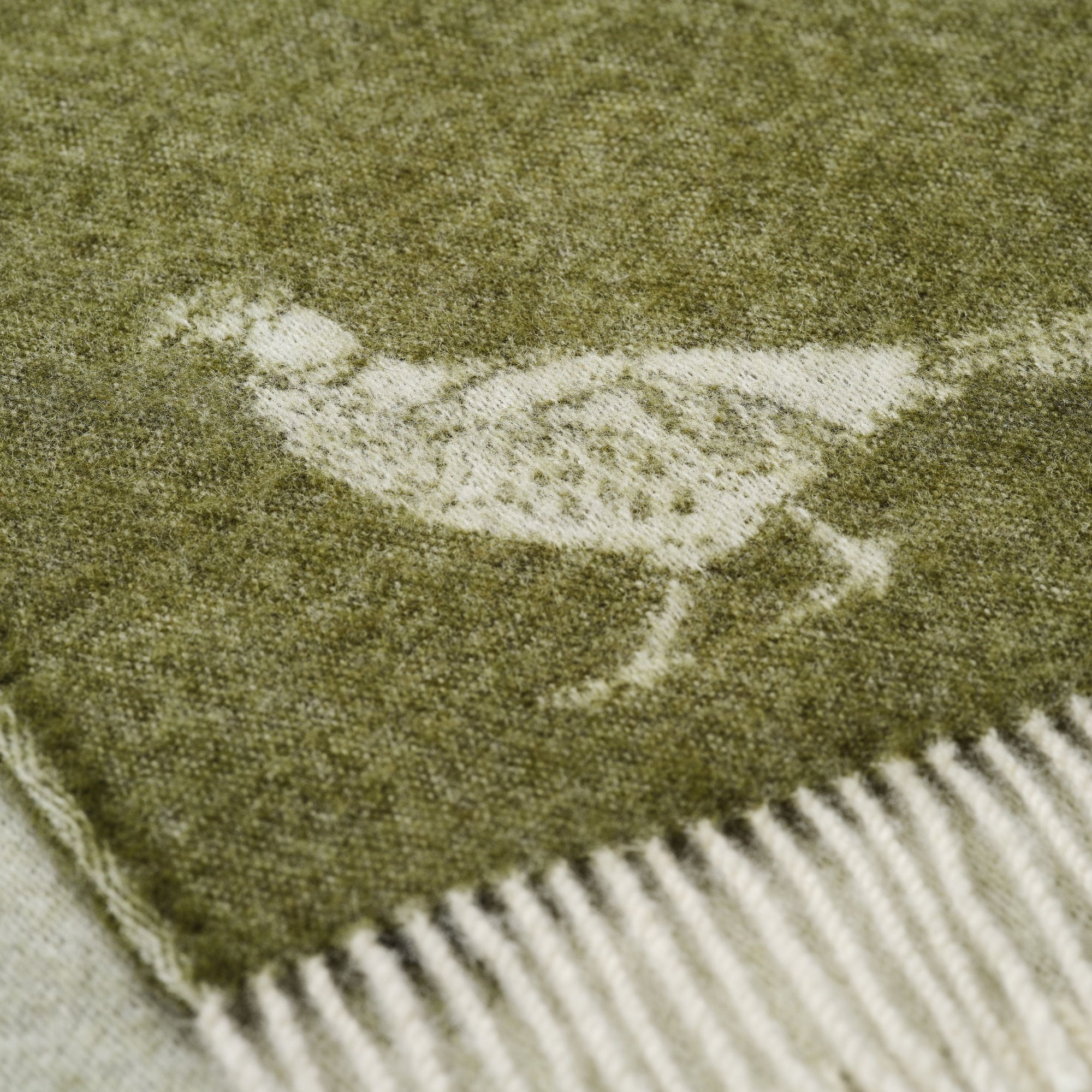 Close-up of a green throw with a white pheasant pattern