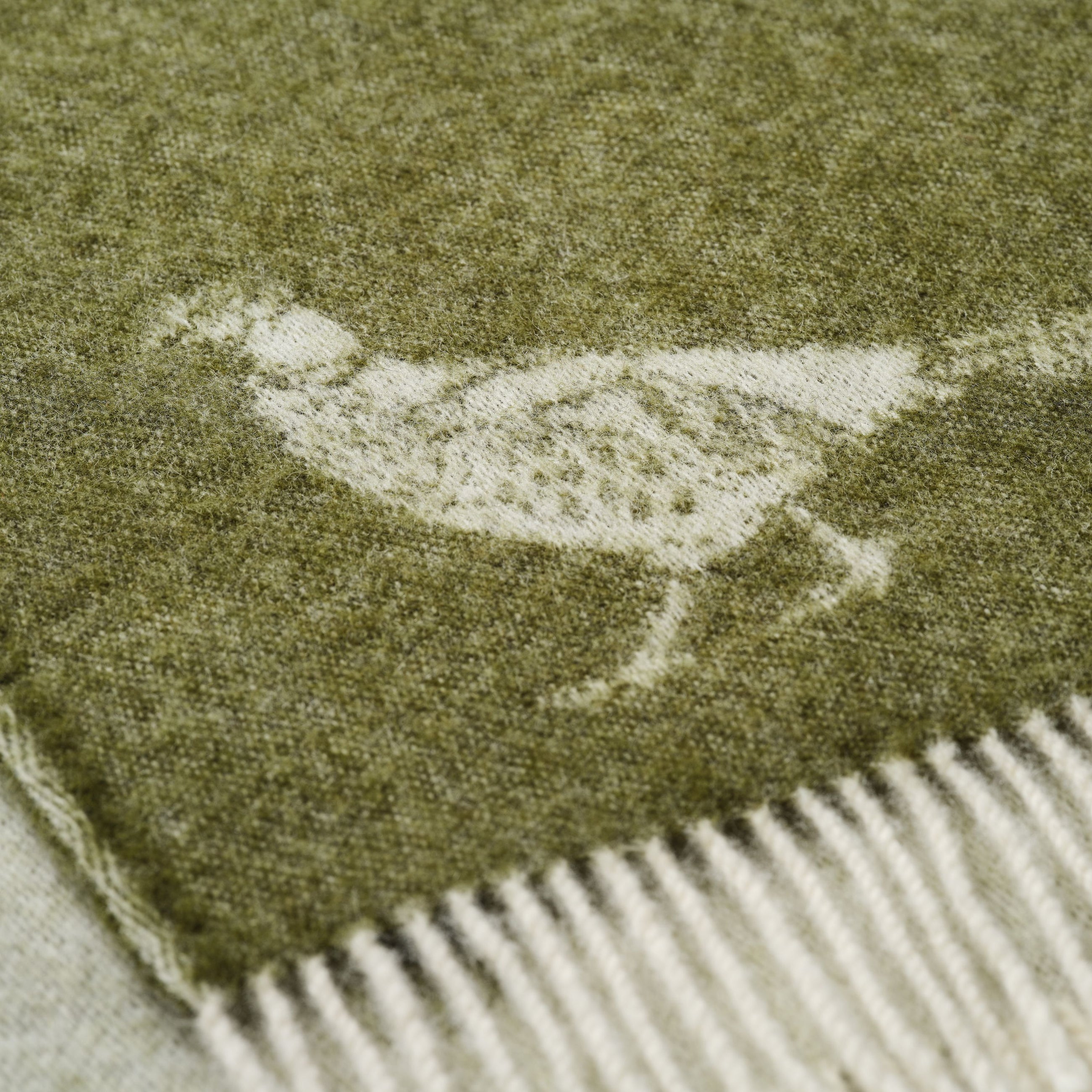 Close-up of a green throw with a white pheasant pattern