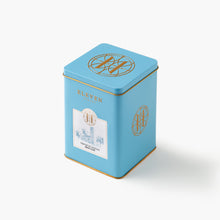 Blue tea canister with gold accents and a Eleven Bibury Hot Chocolate label on a white background