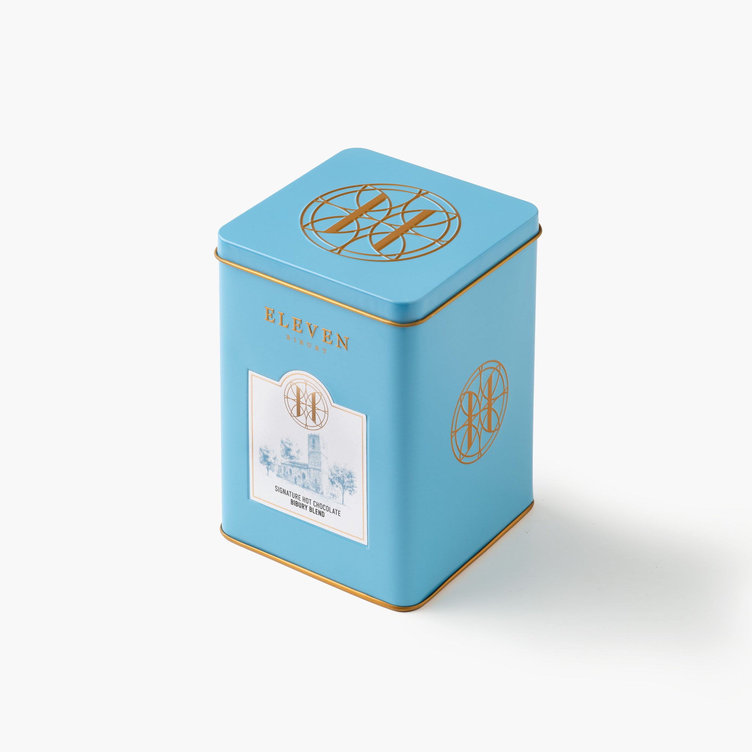 Blue tea canister with gold accents and a Eleven Bibury Hot Chocolate label on a white background