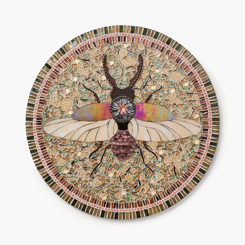 Mosaic artwork of a beetle with colorful wings on a circular plate.