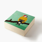 Wooden block with a colorful bird illustration on a green background