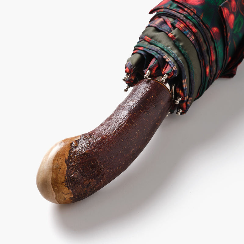Close-up of a wooden umbrella handle with a colorful umbrella partially open on a white background