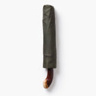 Folded green umbrella with a wooden handle on a white background