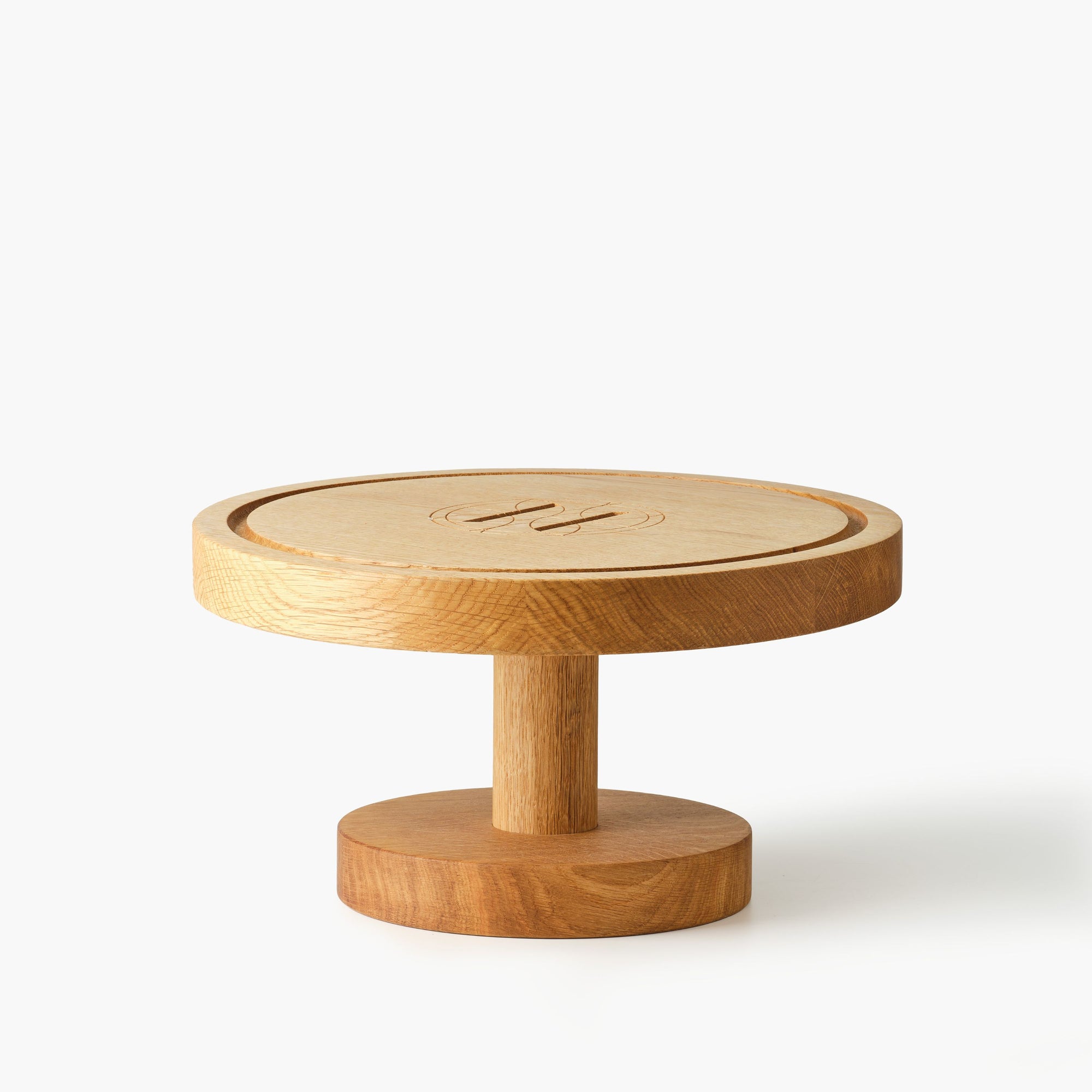 Round wooden cake stand engraved with Eleven Bibury logo on a white background