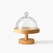 Round wooden cake stand engraved with Eleven Bibury logo with a glass dome on a white background