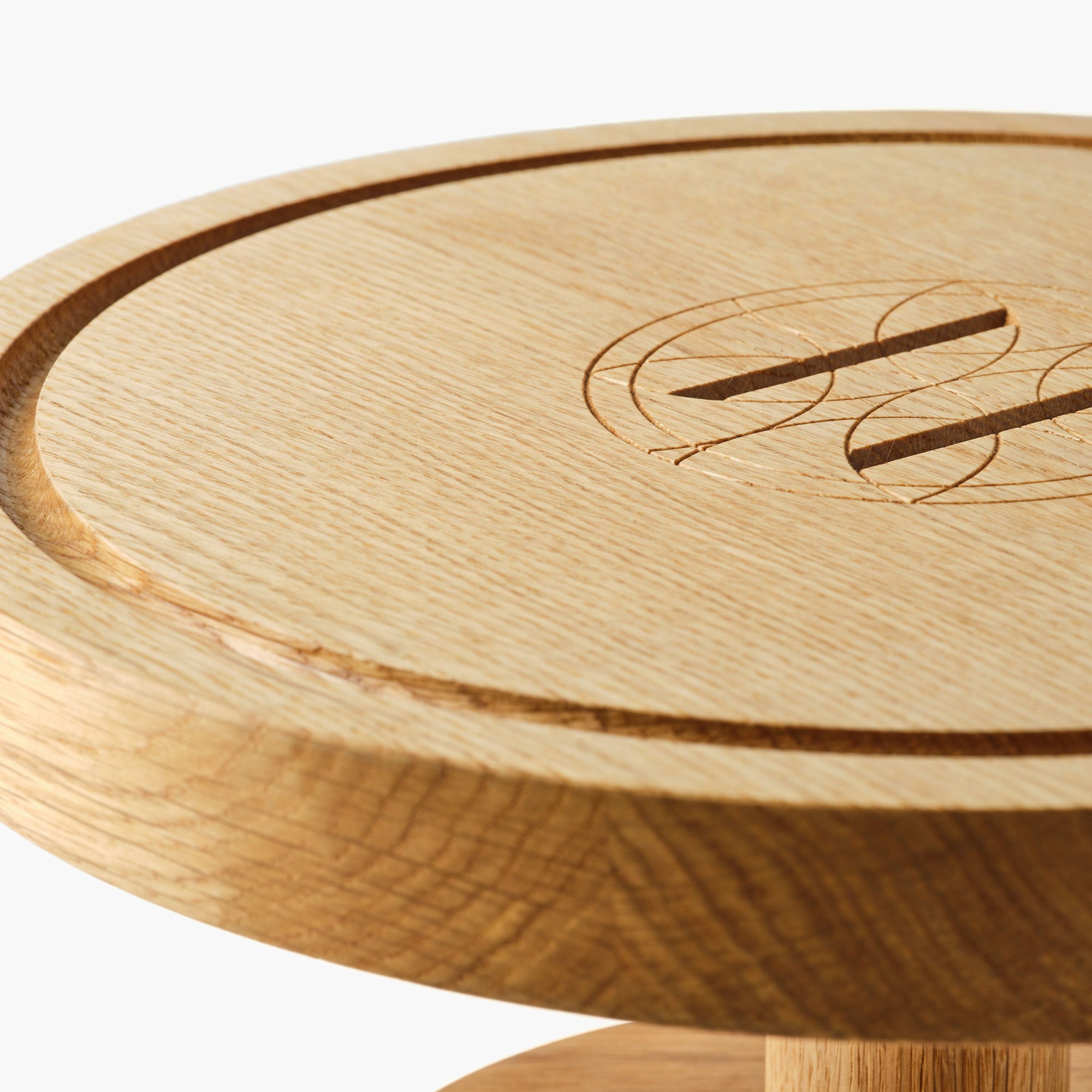 Close up of round wooden pedestal cake stand with engraved Eleven Bibury logo on a white background