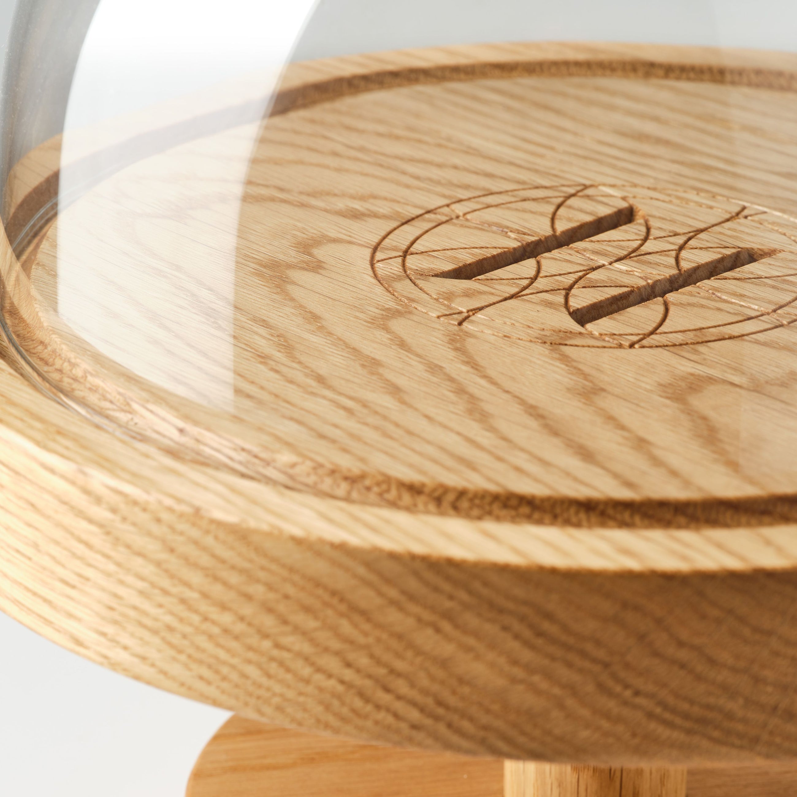 Close-up of a round oak pedestal stand with glass dome on a white background