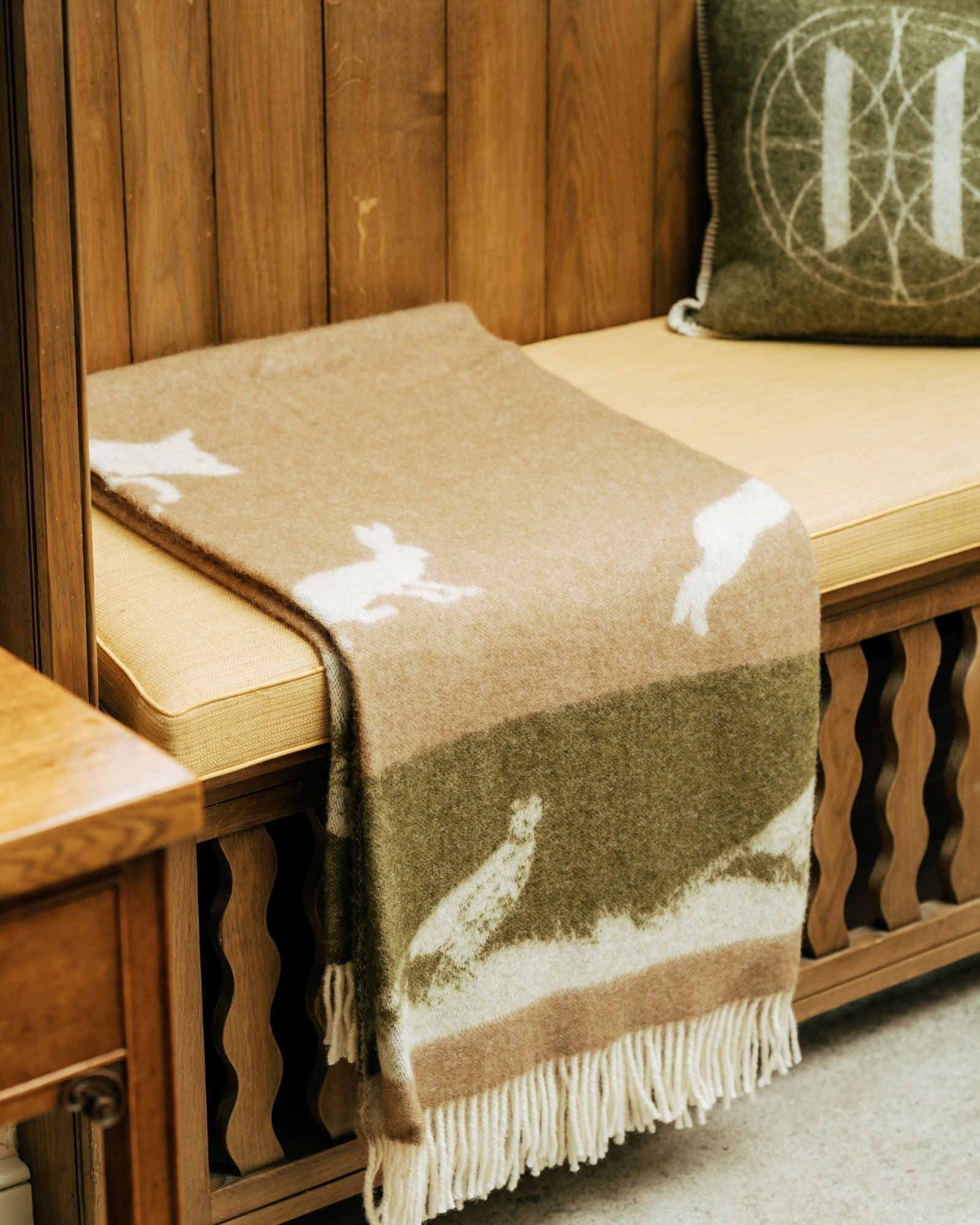 Blanket with pheasant pattern draped over a wooden bench