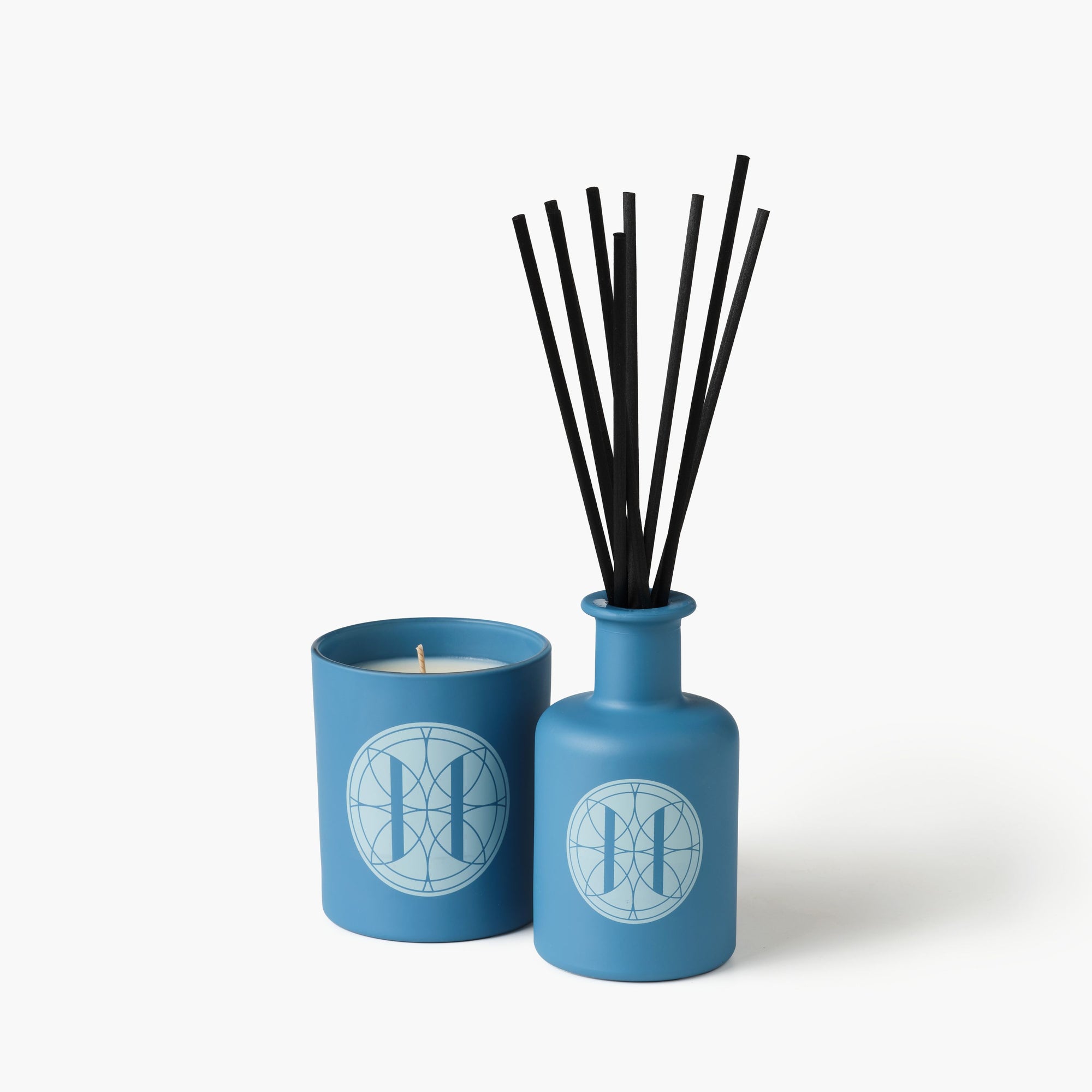 Eleven Bibury 'Rack Isle' blue candle and diffuser set with black sticks on a white background