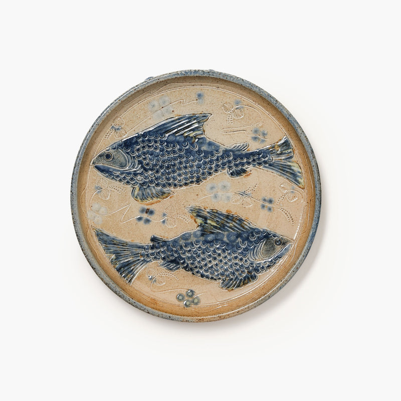 Ceramic plate with blue fish design on a beige background