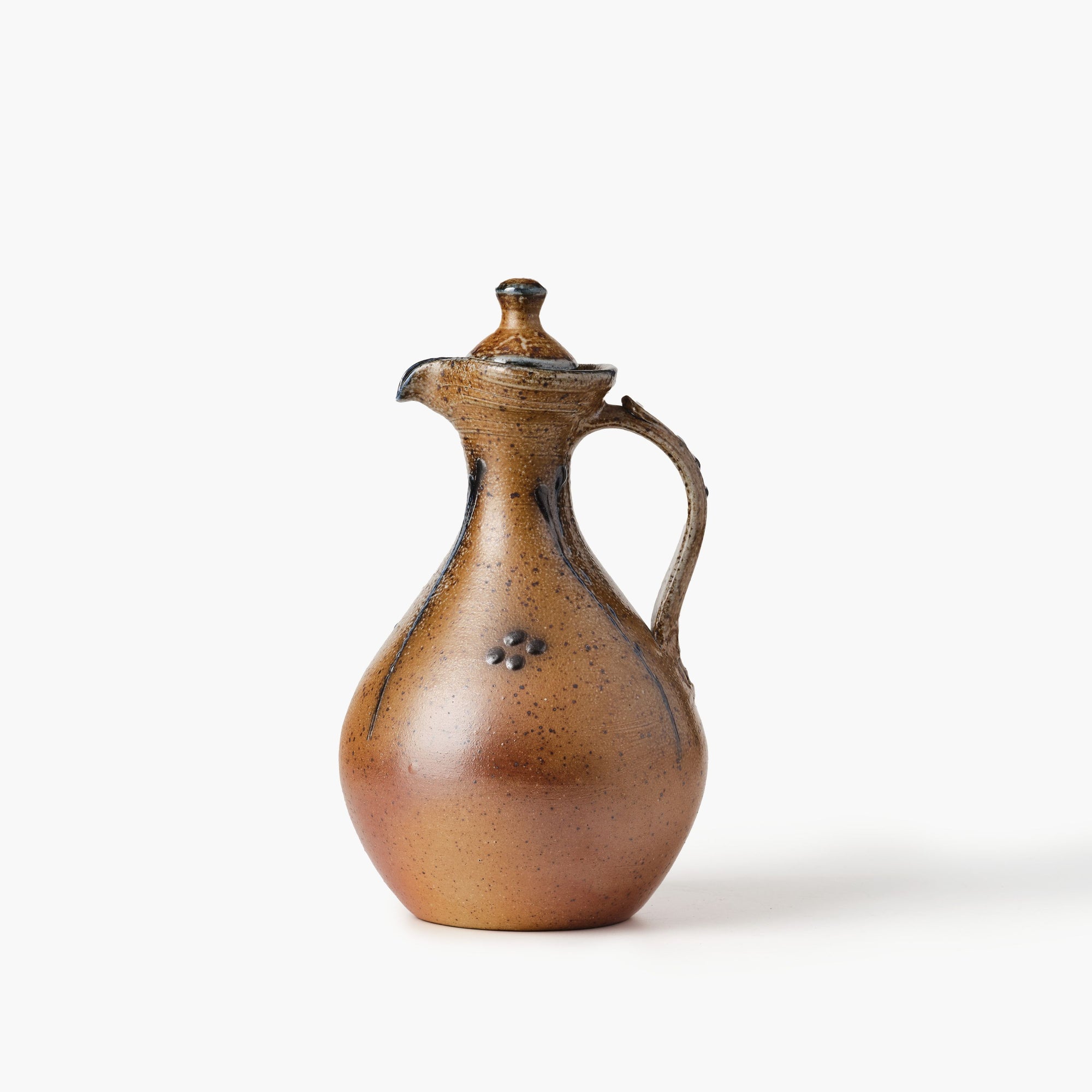 Brown ceramic pitcher with a lid on a white background