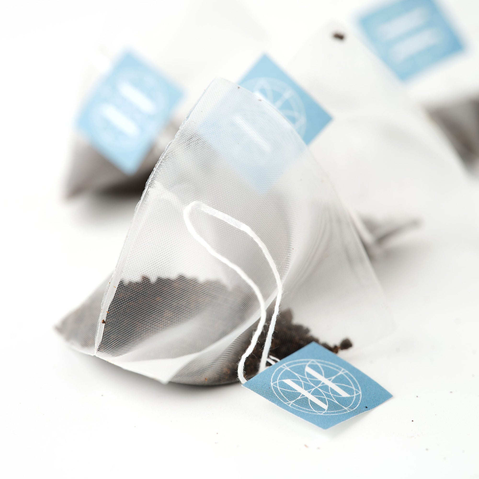 Eleven Bibury Tea bags with blue labels on a white background