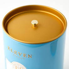 Blue cylindrical tea container with gold lid featuring 'ELEVEN BIBURY' branding.